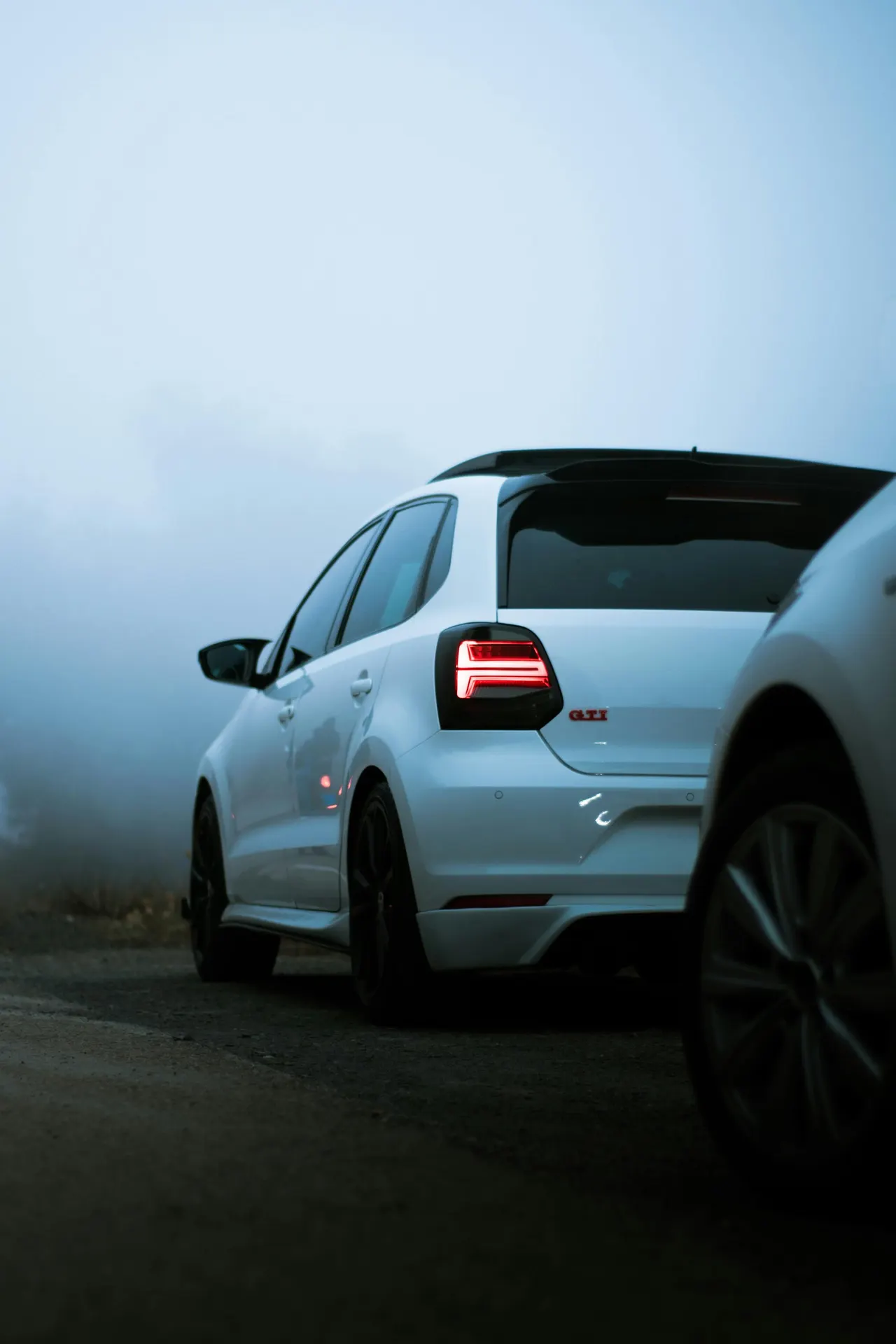 Weißer Volkswagen Polo GTI, ein Kompaktwagen des Volkswagen-Konzerns, auf einer nebligen Straße geparkt